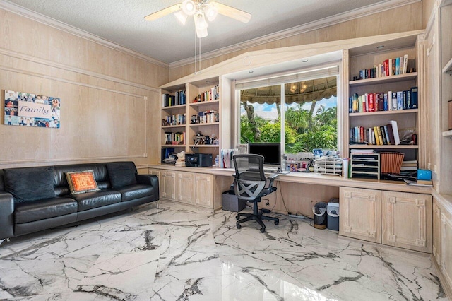 office space featuring wood walls, a textured ceiling, ceiling fan, crown molding, and built in desk