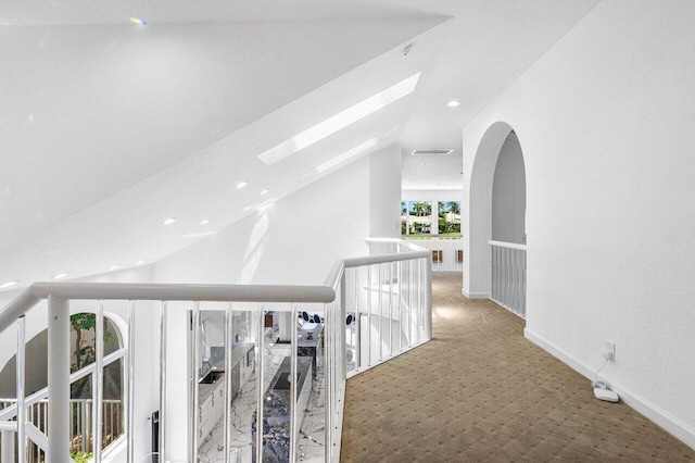 corridor featuring vaulted ceiling with skylight and carpet flooring