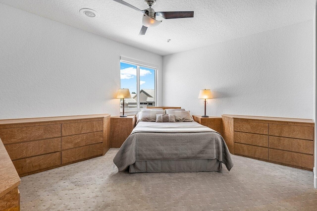 bedroom featuring ceiling fan, a textured ceiling, and light carpet