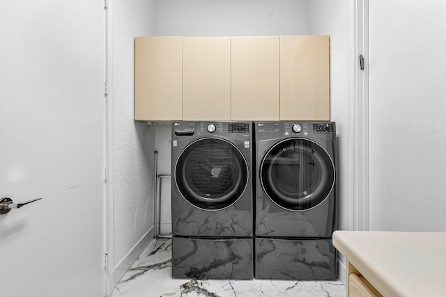 laundry room featuring washer and clothes dryer and cabinets