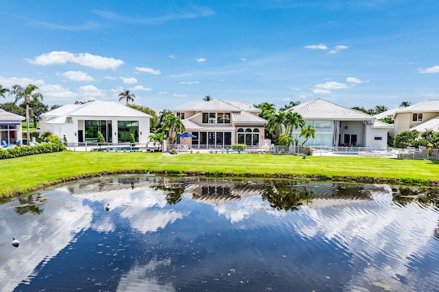 back of property with a water view and a yard