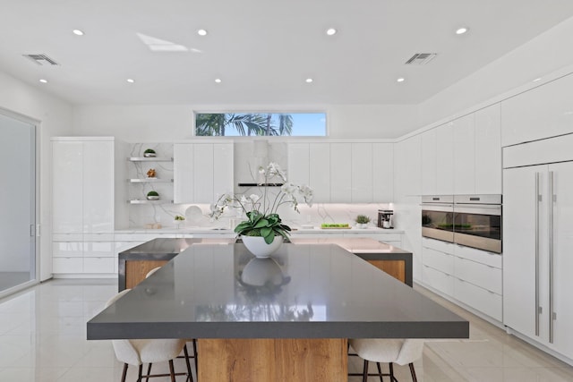 kitchen featuring a large island, stainless steel oven, and white cabinetry