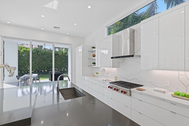 kitchen with white cabinets, sink, tasteful backsplash, wall chimney exhaust hood, and stainless steel gas stovetop