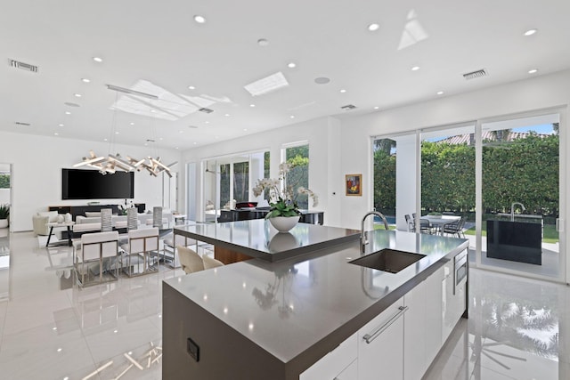 kitchen with white cabinetry, sink, a kitchen island with sink, and decorative light fixtures