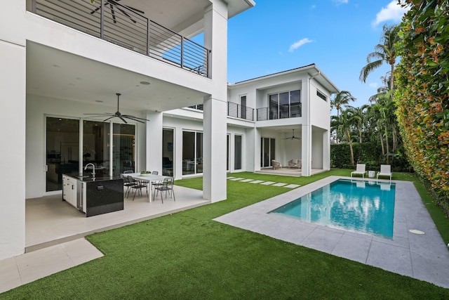 back of house featuring a lawn, ceiling fan, a balcony, and a patio area