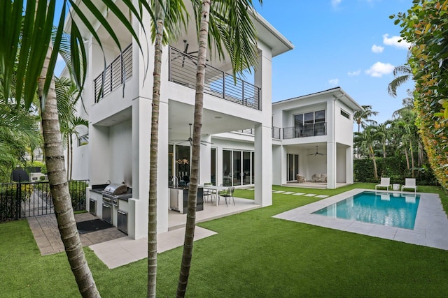 rear view of house featuring exterior kitchen, a yard, a patio, a fenced in pool, and a balcony