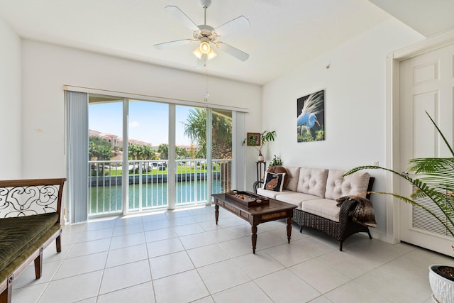 living room with ceiling fan, a water view, and light tile patterned floors