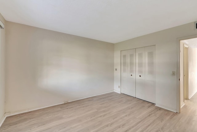 unfurnished bedroom featuring light wood-style floors, a closet, and baseboards