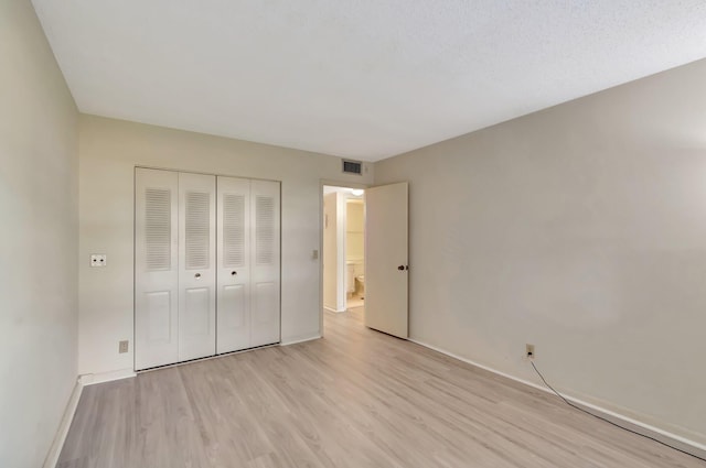 unfurnished bedroom featuring light wood-style flooring, baseboards, and a closet