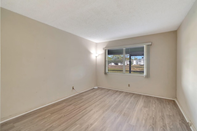 unfurnished room with light wood-style flooring, baseboards, and a textured ceiling