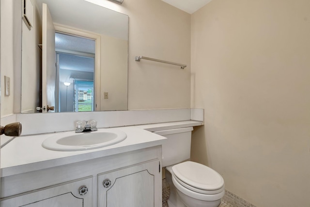 bathroom with toilet, vanity, and tile patterned flooring