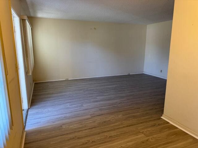 spare room featuring a textured ceiling and dark hardwood / wood-style floors