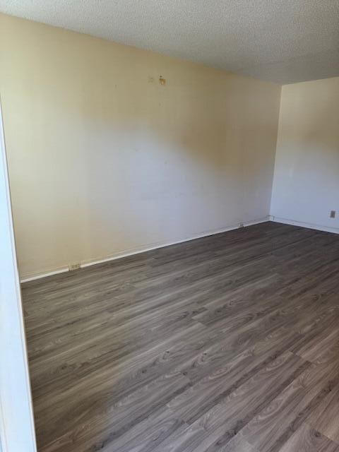 unfurnished room featuring a textured ceiling and dark wood-type flooring