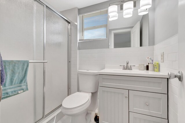 bathroom with toilet, tile walls, a shower with shower door, tasteful backsplash, and vanity