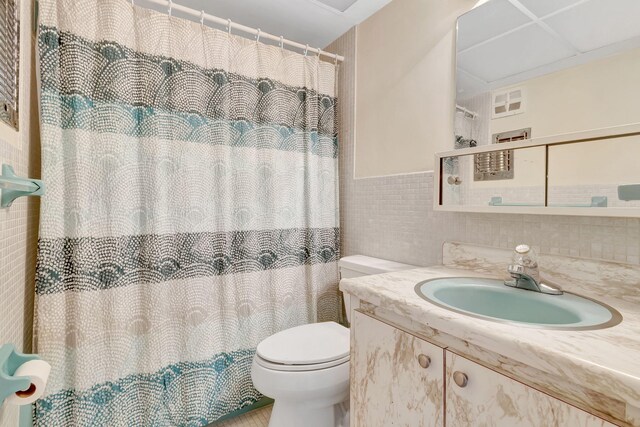 bathroom featuring curtained shower, toilet, tile walls, decorative backsplash, and vanity