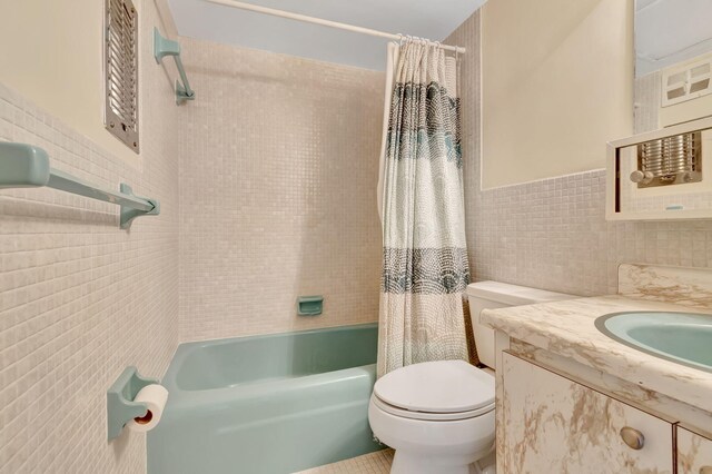 full bathroom featuring vanity, toilet, shower / tub combo with curtain, and tile walls