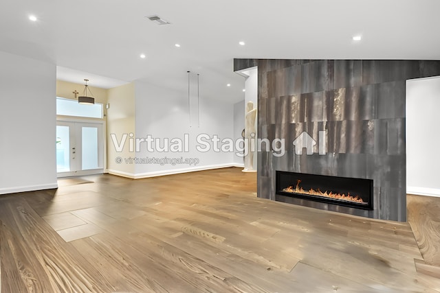 unfurnished living room featuring visible vents, baseboards, french doors, a fireplace, and wood finished floors