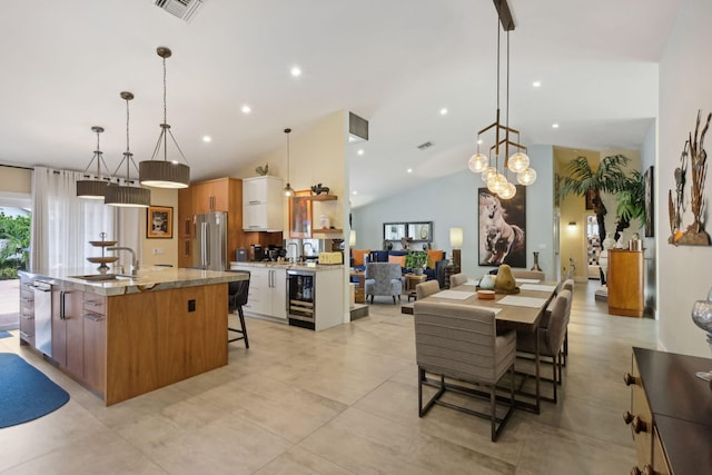 kitchen with a kitchen bar, visible vents, stainless steel appliances, wine cooler, and a large island with sink