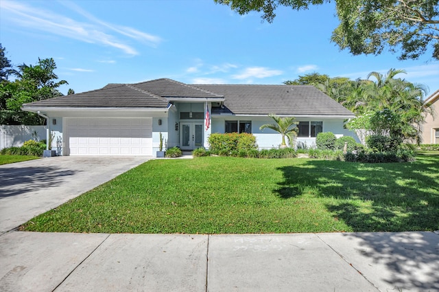 single story home with a front yard, an attached garage, a tile roof, and driveway