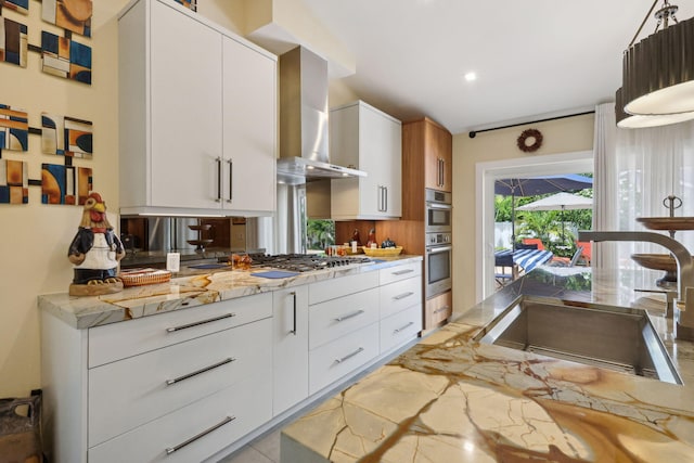 kitchen featuring a sink, stainless steel gas stovetop, white cabinets, wall chimney exhaust hood, and modern cabinets