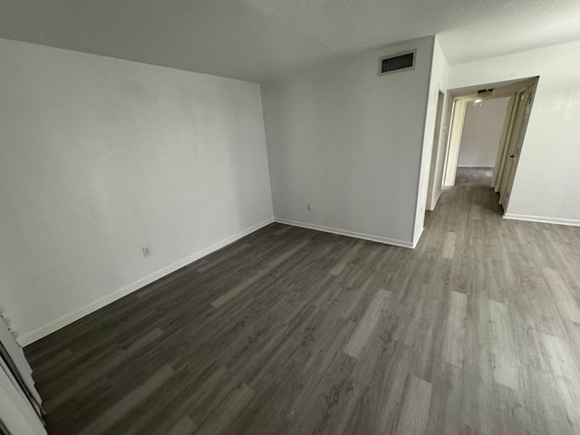 empty room featuring a textured ceiling and dark hardwood / wood-style flooring