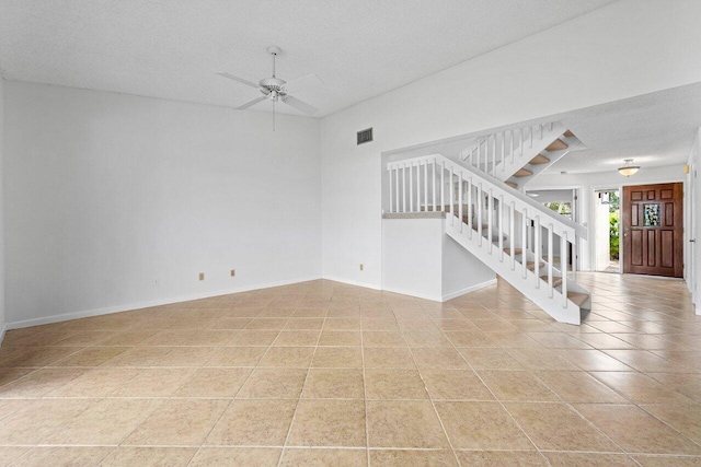 unfurnished living room with ceiling fan, light tile patterned floors, and a textured ceiling