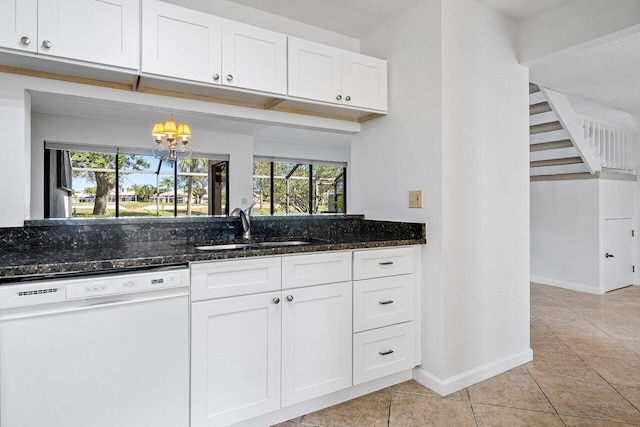 kitchen with white cabinets, dark stone counters, sink, light tile patterned floors, and dishwasher