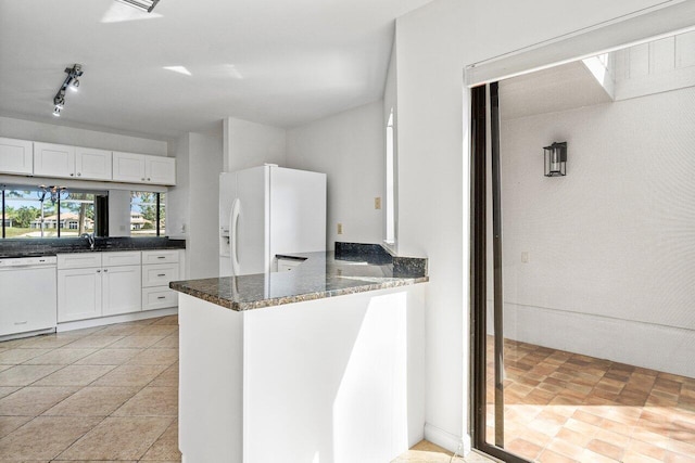 kitchen with kitchen peninsula, white appliances, white cabinetry, and dark stone countertops