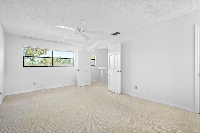 empty room featuring light carpet, ceiling fan, and a textured ceiling