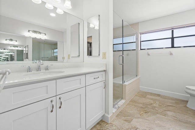 bathroom featuring vanity, a shower with shower door, and toilet