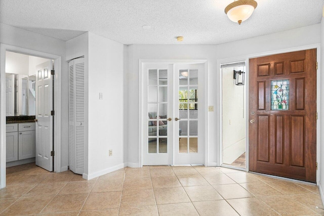 foyer featuring french doors, light tile patterned floors, and a textured ceiling