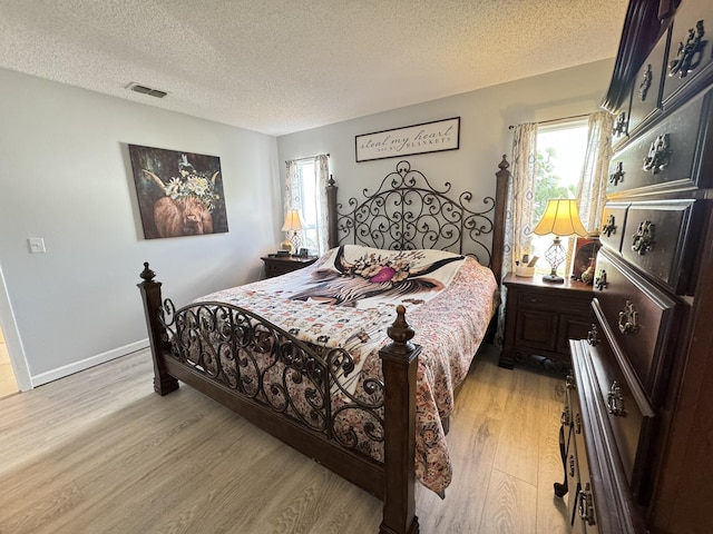 bedroom with a textured ceiling and light wood-type flooring