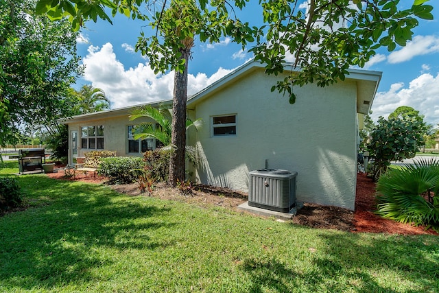 exterior space featuring central air condition unit and a lawn