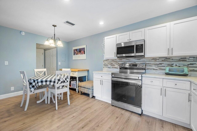 kitchen featuring pendant lighting, stainless steel appliances, white cabinetry, and light hardwood / wood-style floors