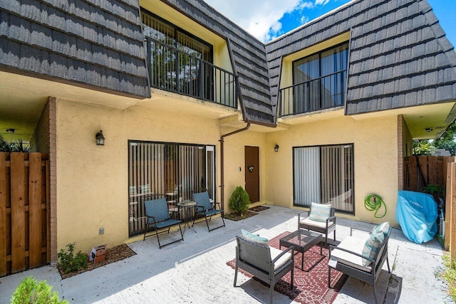 back of property with a balcony, outdoor lounge area, and a patio