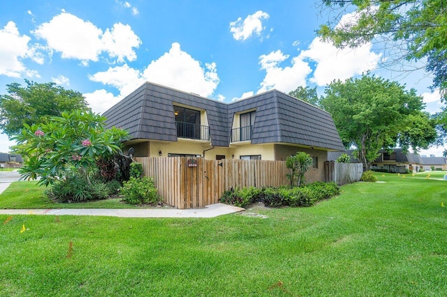 view of property exterior with a balcony and a lawn