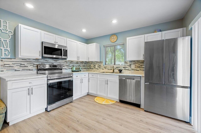 kitchen featuring light hardwood / wood-style flooring, backsplash, appliances with stainless steel finishes, and white cabinetry