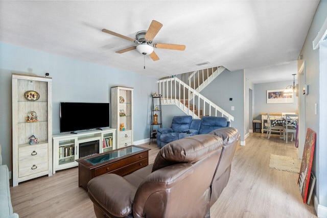 living room featuring ceiling fan with notable chandelier, wood-type flooring, and a textured ceiling