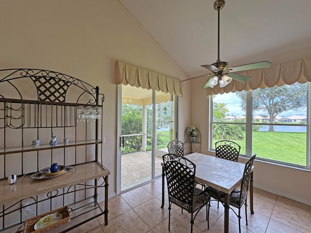 dining area with ceiling fan, light tile patterned floors, and vaulted ceiling