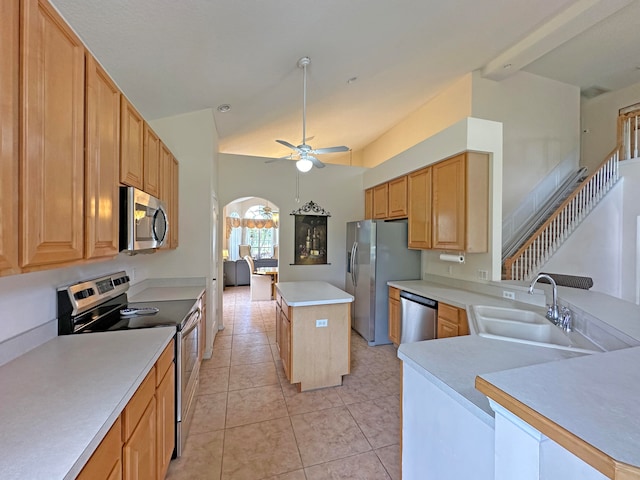 kitchen with light tile patterned floors, stainless steel appliances, a center island, ceiling fan, and sink