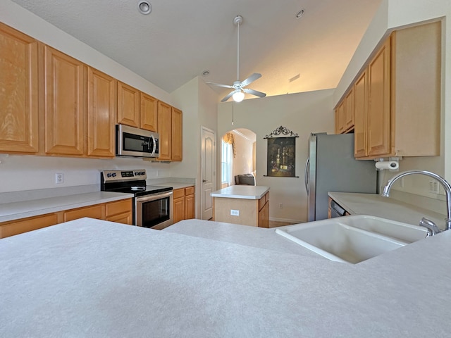 kitchen with appliances with stainless steel finishes, vaulted ceiling, a center island, ceiling fan, and sink