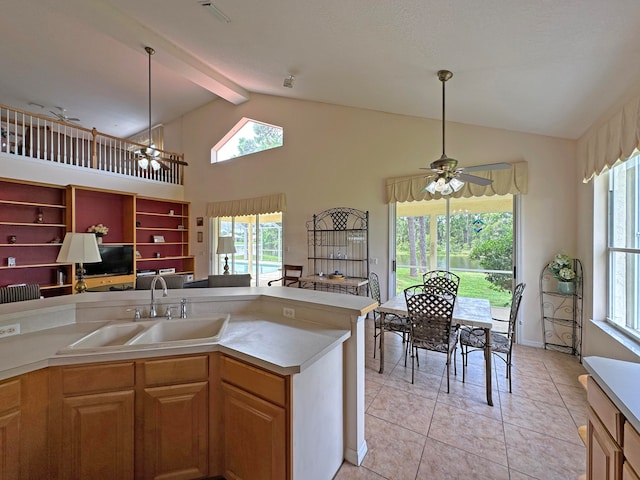 kitchen with hanging light fixtures, light tile patterned flooring, ceiling fan with notable chandelier, beamed ceiling, and sink