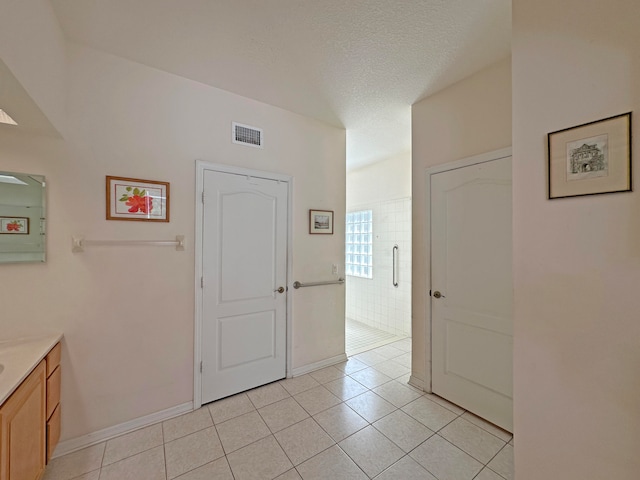 empty room with a textured ceiling and light tile patterned floors