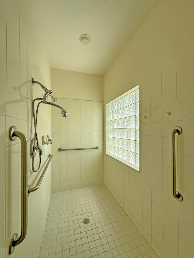 bathroom featuring a textured ceiling and a tile shower