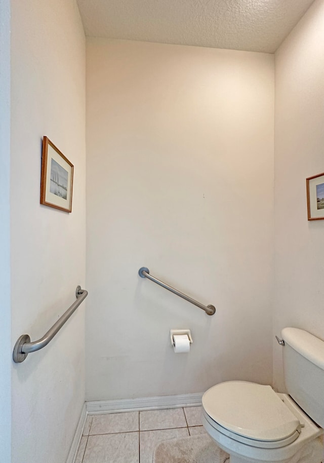 bathroom with a textured ceiling, toilet, and tile patterned floors