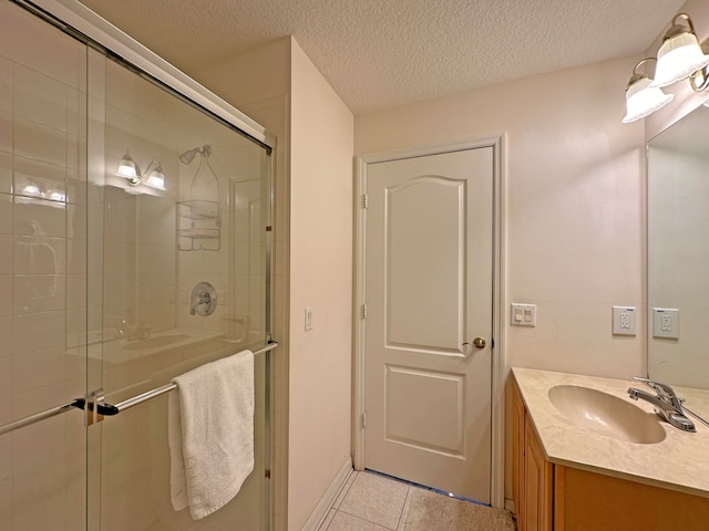 bathroom with vanity, a textured ceiling, a shower with door, and tile patterned floors