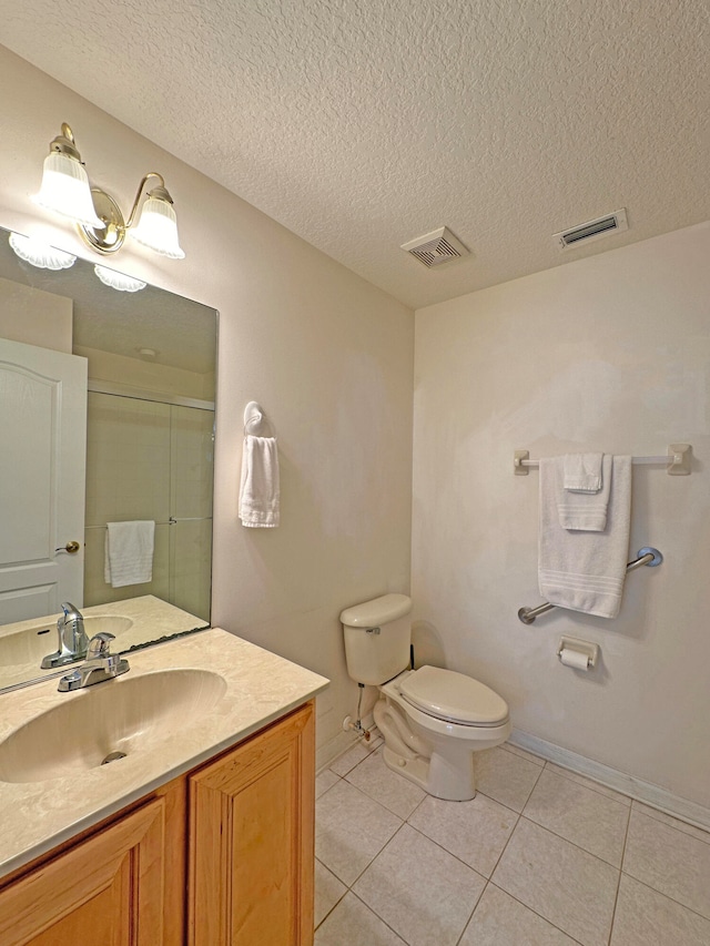 bathroom with vanity, walk in shower, a textured ceiling, tile patterned flooring, and toilet