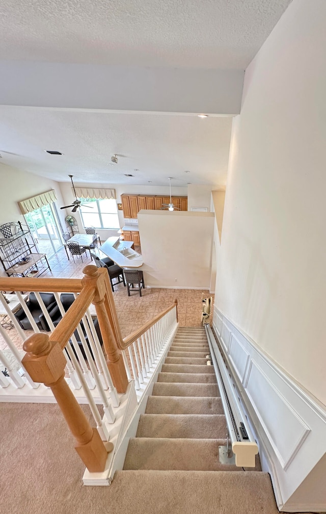 staircase with carpet floors and a textured ceiling