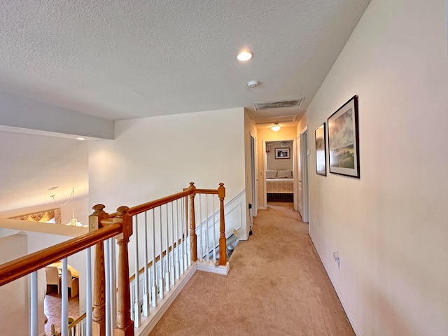 hall with light colored carpet, a textured ceiling, and lofted ceiling