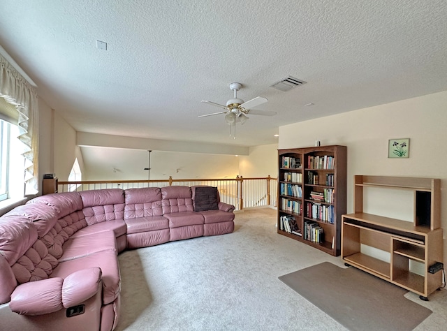 carpeted living room featuring ceiling fan and a textured ceiling